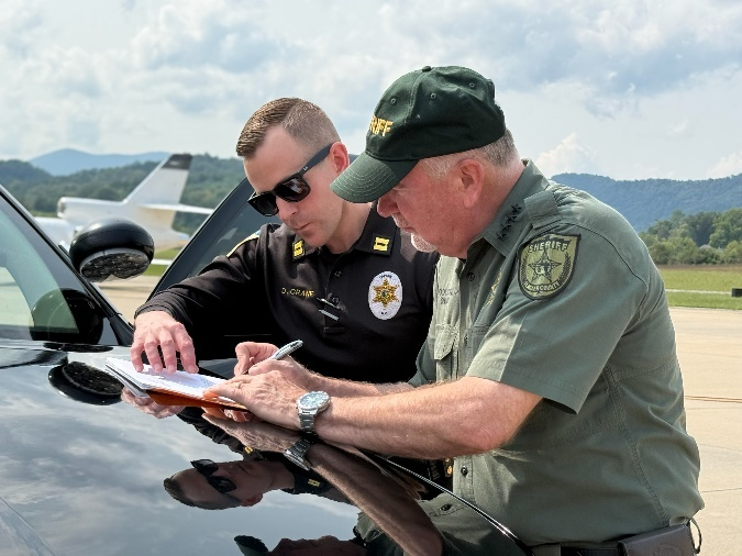  Flagler County Sheriff Rick Staly, right, signs documents taking Kermit Booth into custody in Franklin, N.C., on Friday, Sept. 5, 2025