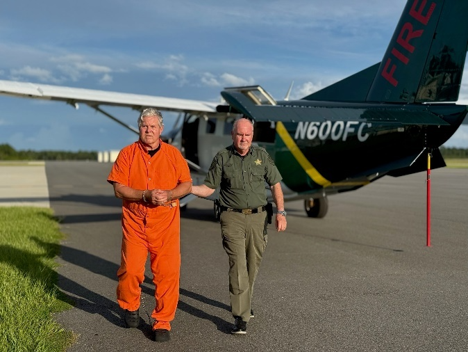 Kermit Booth, left, is escorted by Flagler County Sheriff Rick Staly, right, after arriving in Palm Coast, Fla., on Friday, Sept. 5, 2025.
